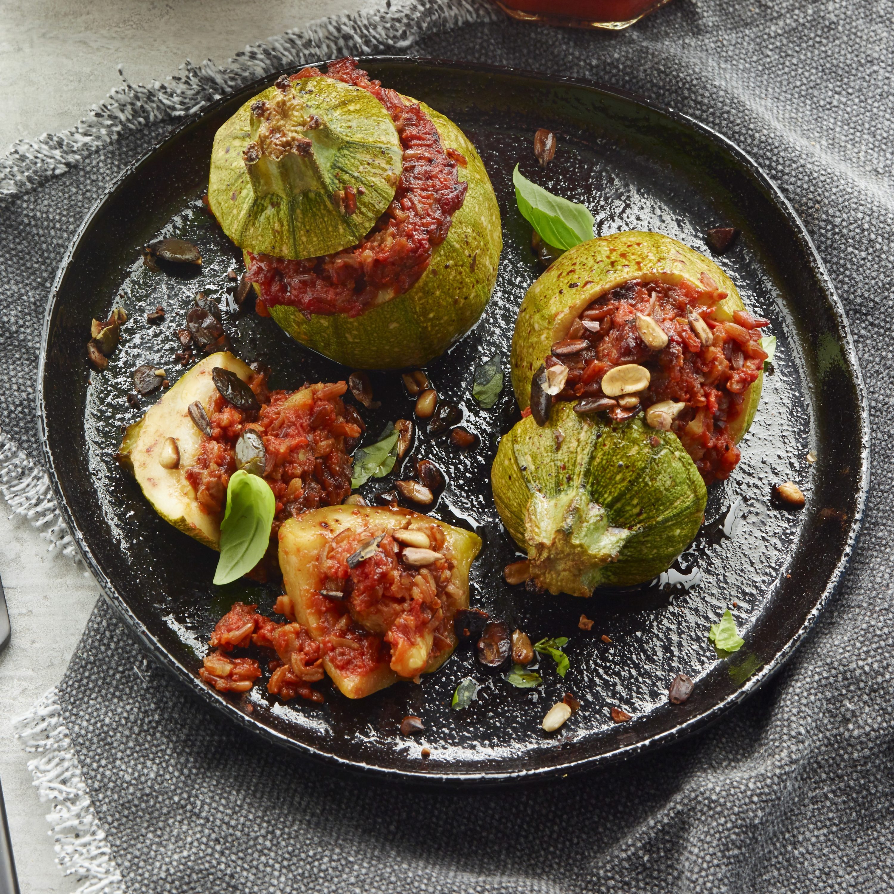 Runde fyldte zucchini med tomatsauce med chilipeber, vilde ris og ristede frø Runde fyldte zucchini med tomatsauce med chilipeber, vilde ris og ristede frø