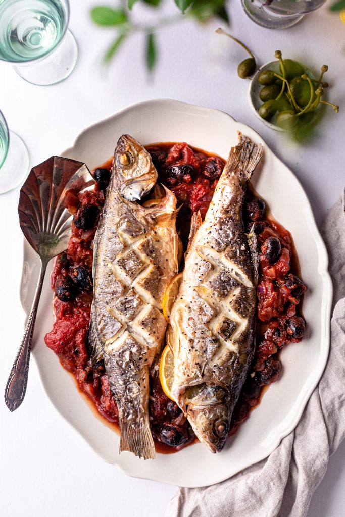 Baked Whole Sea Bass with black olives, tomato and capers sauce Baked Whole Sea Bass with black olives, tomato and capers sauce